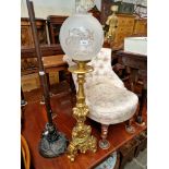 A floor lamp with gilt pedestal base and glass shade.