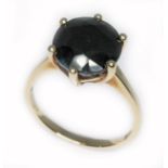 A 9ct gold sapphire solitaire ring, the dark blue/black round mixed cut stone measuring approx. 10mm