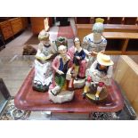 A group of five Staffordshire pottery figures including girl reading and shepherd shearing a sheep.