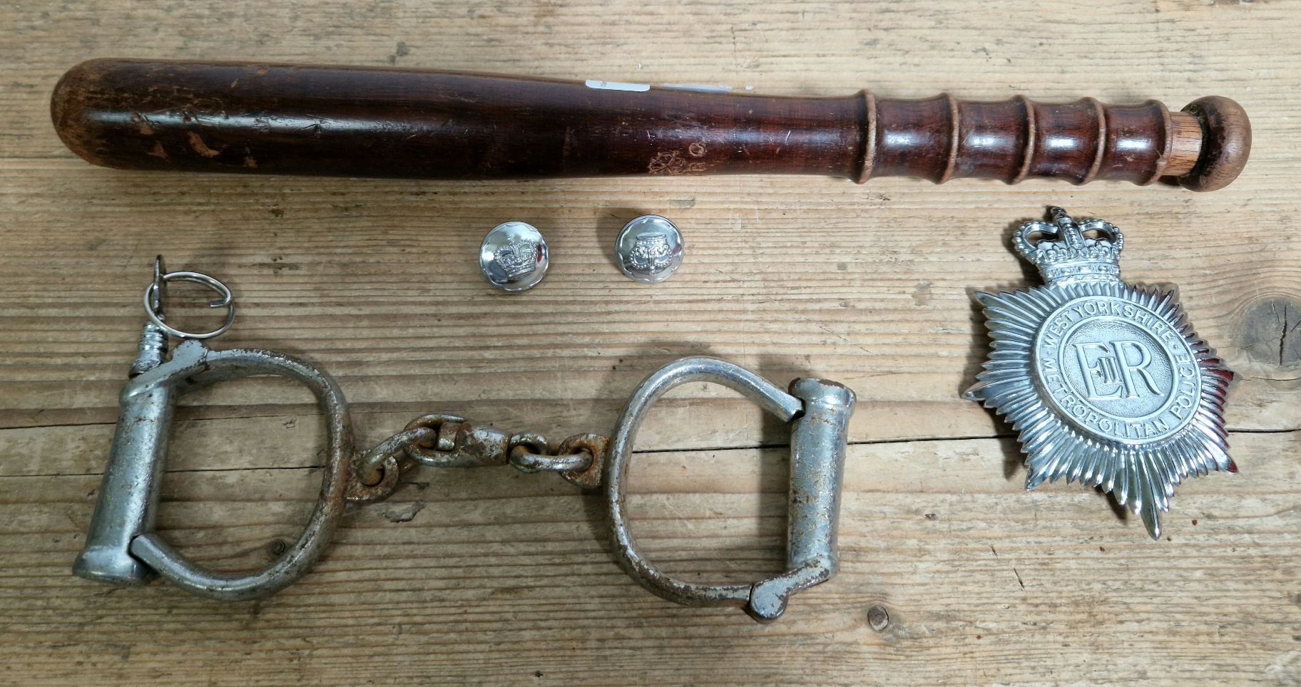 A wooden truncheon, West Yorkshire police badge and a pair of early 20th century handcuffs
