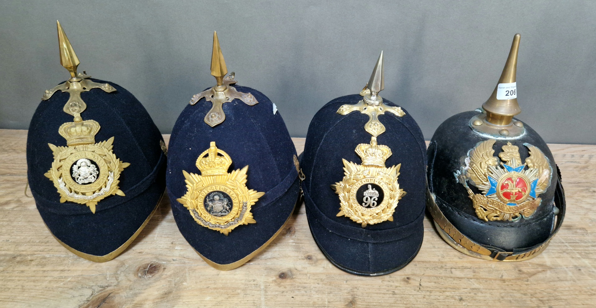 A group of four military helmets to include two Manchester Regiment Officer's blue cloth helmets,