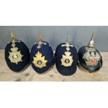 A group of four military helmets to include two Manchester Regiment Officer's blue cloth helmets,