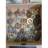 A collection of military cap badges and plates to include Manchester Regiment, 33rd Lancashire