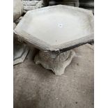 A hexagonal bird bath on plinth.