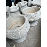 A pair of ornate planters on plinths.