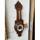 A carved oak aneroid barometer/thermometer.