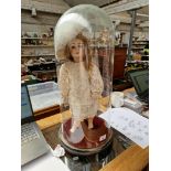A Limoges Cherie porcelain doll with composition body and jointed limbs, under glass dome.