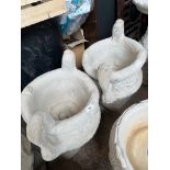 A pair of urn planters on plinths.