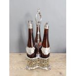 A silver plated three bottle tantalus, the bottles with cast silver decanter labels by Nat Joseph,
