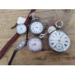 A group of three silver pocket watches and two silver wristwatches.