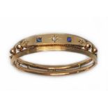 A late Victorian/Edwardian diamond and sapphire bangle, sponsor 'NBs', marked '9ct', wt. 18.5g.