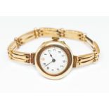 A late Victorian/Edwardian ladies 9ct gold watch and strap, white enamel dial with gold dot minute