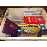 A wooden crate of items including a Back to the Future RC car, coin sets, nautical themed key rings.