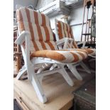 A pair of white plastic garden sun lounger/chairs.