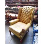 A mustard leather chesterfield armchair.