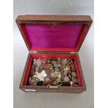 A wooden box containing various UK and world coins, tokens, etc.