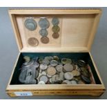 A lidded wooden box containing assorted world coins and tokens.