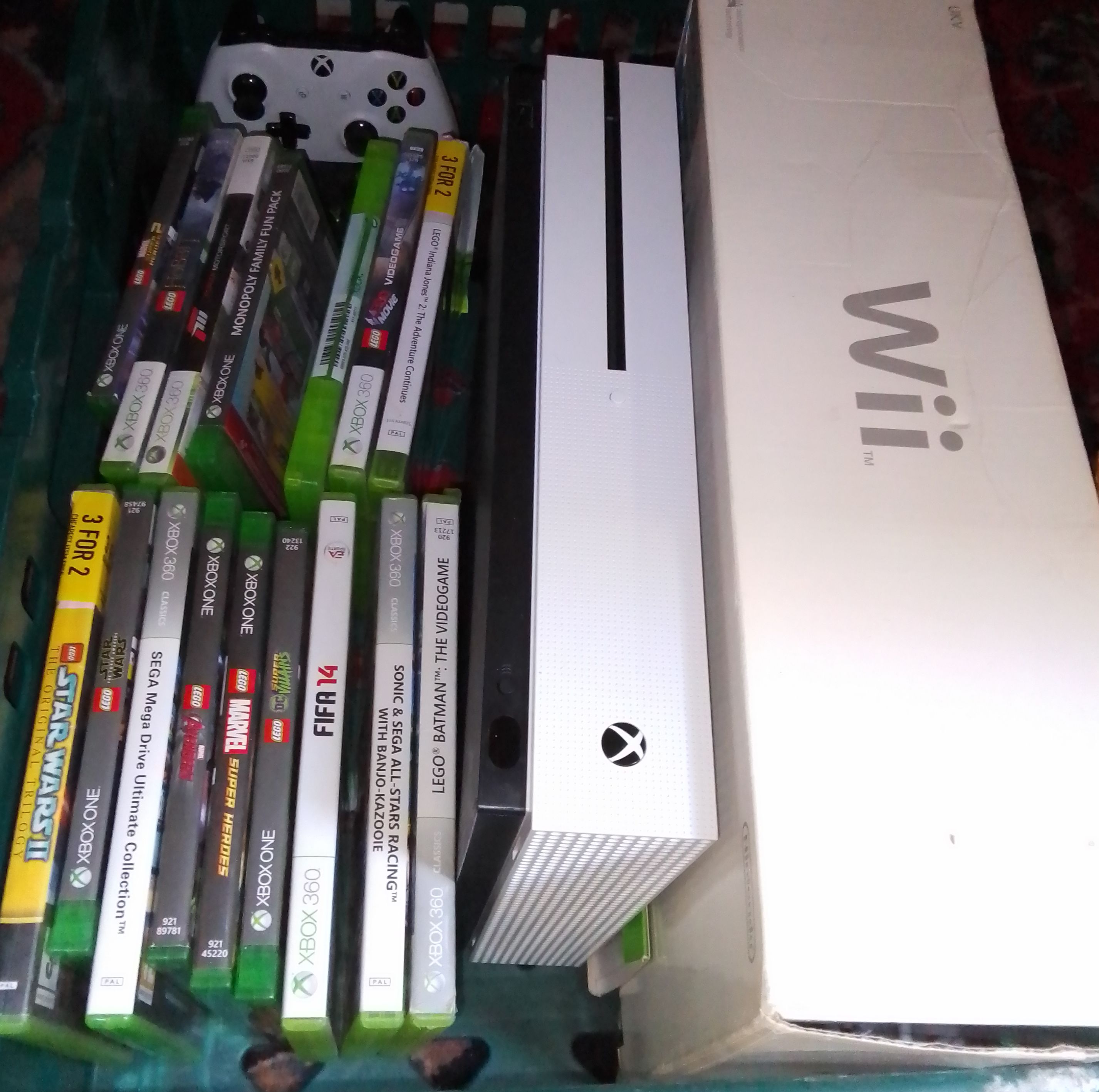 An Xbox One with games together with a Wii console.