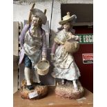 A pair of plaster figurines, each carrying baskets