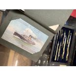 An album of vintage postcards and a technical drawing set in rosewood case.