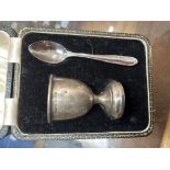 A hallmarked silver egg cup on a case, with non matching plated spoon