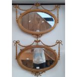 A pair of Edwardian gilt framed oval mirrors, the frames having swag and bow decoration, 67cm x 51cm