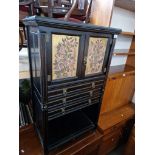 A late Victorian Gillows Aesthetic Movement ebonised music cabinet with painted panels to the doors,