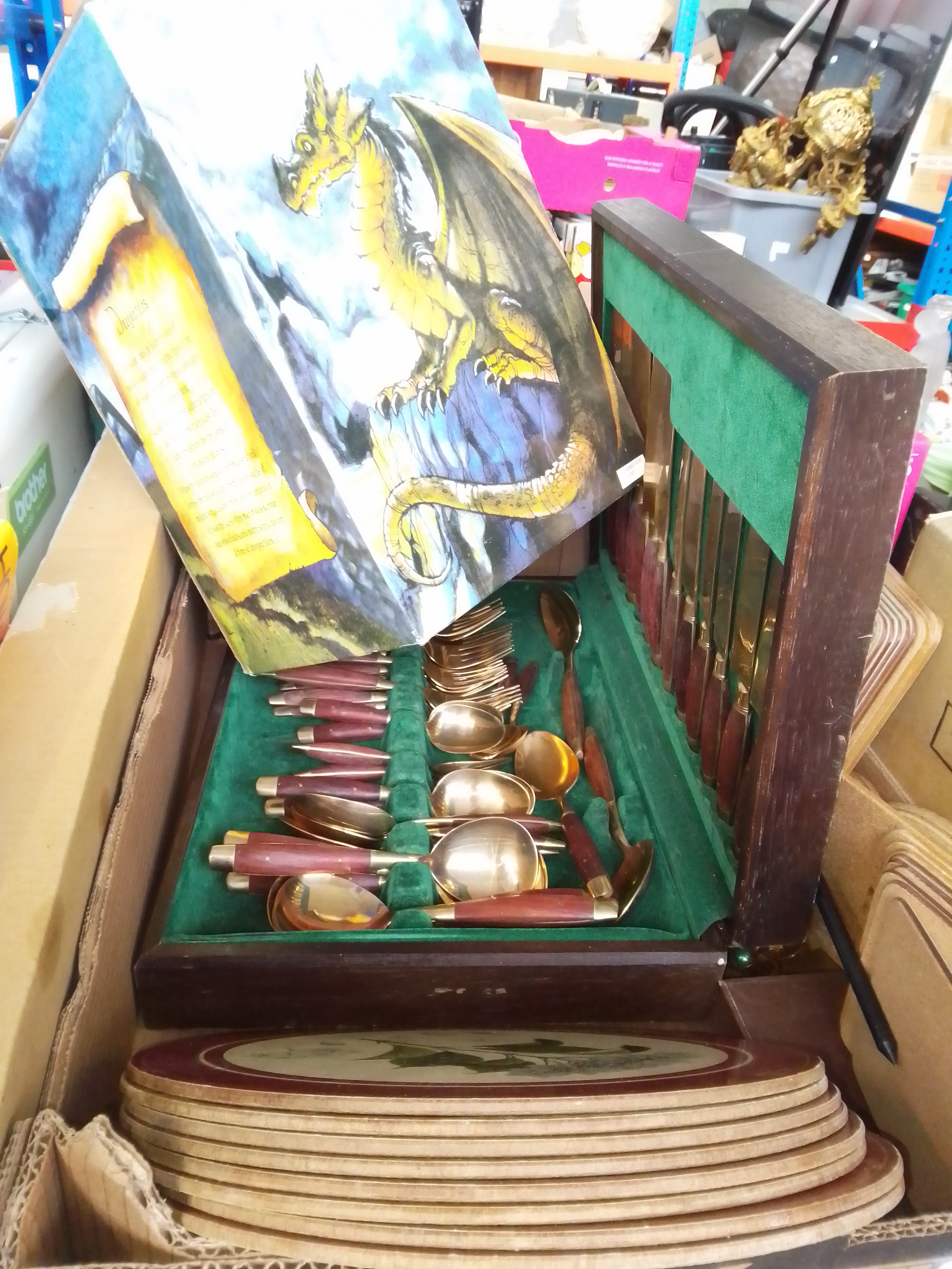 A box of misc items including canteen of cutlery, table mats, Dragon Tales figure