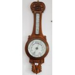 A carved oak aneroid barometer.