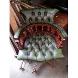 A green leather Chesterfield captain's chair.