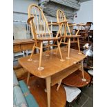 An Ercol light elm extending dining table and two 'Quaker' carver chairs.
