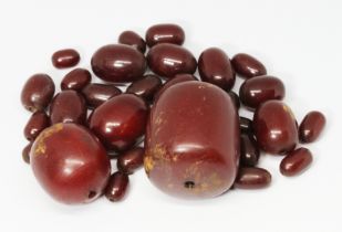 An assortment of loose marble cherry bakelite beads, the largest barrel shaped bead measuring