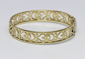 A 9ct gold pierced bangle, wt. 18.2g, diam. 5.5cm. Condition - slight play in hinge, clasp and