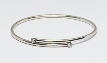 An 18ct gold diamond bangle, the two round brilliant cut diamonds weighing approx. 0.10cts each,