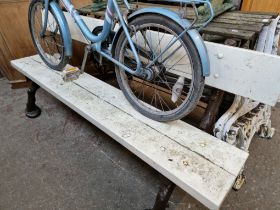 A heavy duty garden bench on wrought iron supports