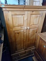 A waxed pine double wardrobe with drawers to base.