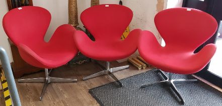 A set of three 'Swan' swivel chairs in red upholstery on chrome bases, designed by Arne Jacobsen.