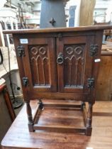 An oak side cabinet with Gothic style panels to the doors.