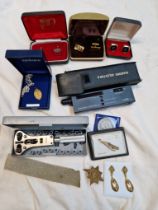 A box containing a diamond tester (appears to be working), watch back removal set, tie clips, cuff