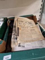 A box of mixed items including boxed cutlery, book, and vintage newspapers