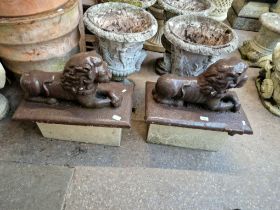 Two ornamental concrete lions on separate concrete blocks