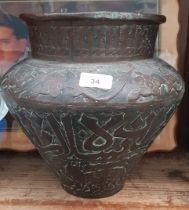 An Eastern bronze urn decorated with flowers and Islamic writing.