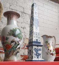 A large jug with fruit pattern, a large blue and white obelisk, and a large oriental vase