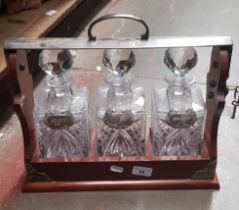 A three bottle mahogany tantalus with cut glass decanters & hallmarked silver labels for whiskey,
