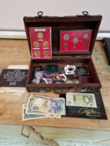 A box of assorted UK and world coins and banknotes including commemorative crowns, coin sets, etc.