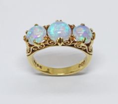 A three stone opal ring, scroll setting with three round opal cabochons, hallmarked 18ct gold,