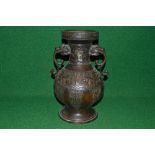 Oriental unsigned bronze two handle vase having raised decoration with dragons head formed handles -