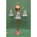 Brass three branch table lamp having reeded scrolled branches ending in down hanging frosted glass