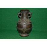 Oriental bronze two handle vase having raised decoration with birds head formed handles and four