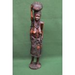 Large hardwood African carved figure of semi nude lady carrying basket of fish on her head, standing